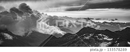 Rocky alpine mountains morning panorama. Cloudy sunrise on summer day. Grossglockner Mountain, Hohe Tauern National Park, Austrian Alps. Black and white image. 133578289
