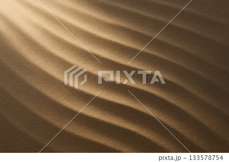 金色の光が描く砂の波紋が穏やかに広がる高級感のある背景 133578754