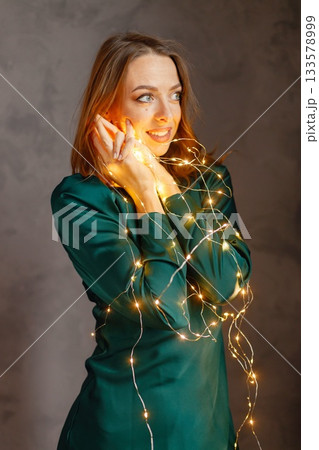Portrait of a young woman celebrating Christmas Eve. Model posing for a photo. Woman wearing green dress. 133578999
