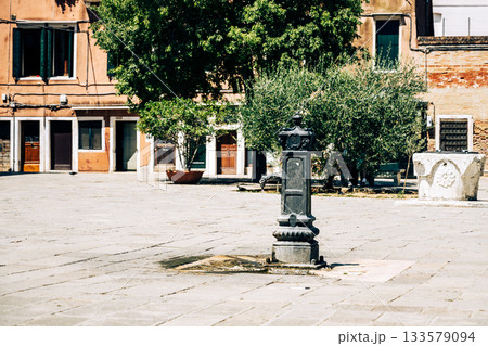 A historic water fountain stands prominently in the Venetian Ghetto, surrounded by serene architecture and greenery, capturing the essence of Jewish heritage in Venice, Italy. 133579094