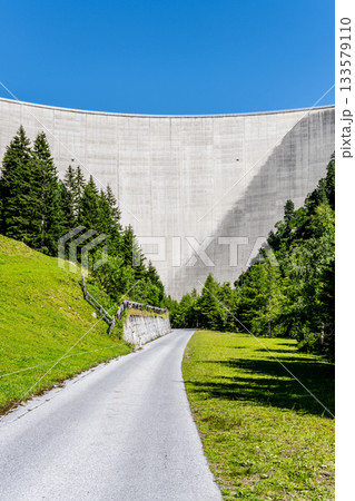 Huge concrete apline dam on sunny summer day. Zillergrundl Speicher, Zillertal Alps, Austria Huge concrete apline dam on sunny summer day. Zillergrundl Speicher, Zillertal Alps, Austria 133579110