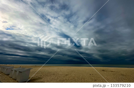 A Dramatic and Beautiful Cloudy Sky Over a Serene Beach Landscape in the Evening Light 133579210