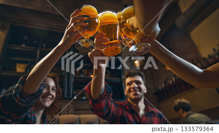 Friends toasting beer glasses in cozy pub celebration scene Friends toasting beer glasses in cozy pub celebration scene 133579364