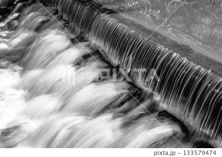Small waterfall on the forest stream. Gaden stone sluice in tranquil forest mood. Black and white image. 133579474
