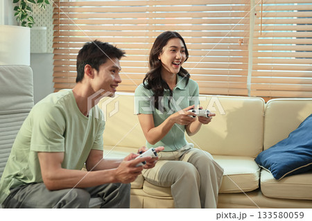 Happy couple playing video games together at home 133580059