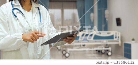 Female doctor in confident with digital tablet in hand with patient bed in hospital room 133580112