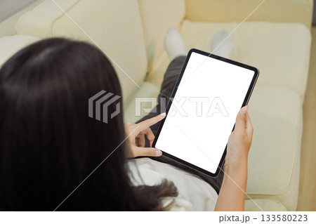 Close up view of a woman using blank screen digital tablet on sofa Close up view of a woman using blank screen digital tablet on sofa 133580223