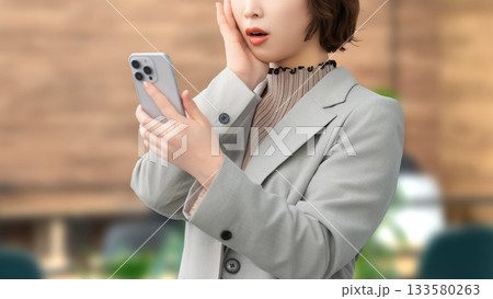 スマートフォンの画面を見て驚くビジネスウーマン スマートフォンの画面を見て驚くビジネスウーマン 133580263