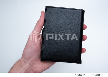 Black Leather Wallet in Male Hand on Light Black Leather Wallet in Male Hand on Light 133580359
