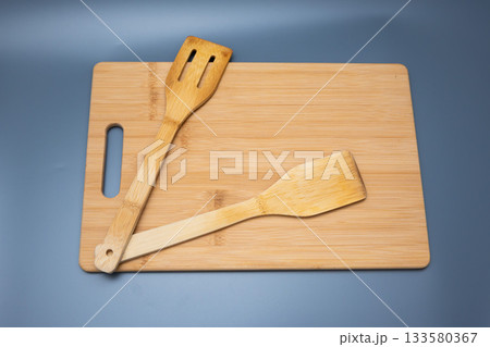 Spatulas on Bamboo Board Against Blue Gradient 133580367