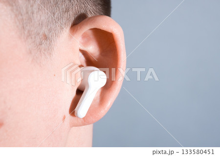 Inserting White Earbud into Ear 133580451