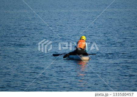 One man on a sap board swims on a lake on a bright day 133580457