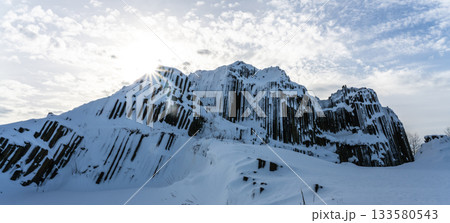 Panska skala - rock formation of pentagonal and hexagonal basalt columns. Looks like giant organ pipes. Covered by snow and ice in winter time. Kamenicky Senov, Czech Republic. 133580543