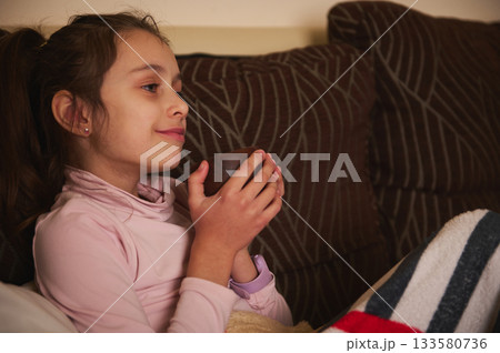 Young Girl Relaxing At Home Holding A Cup On Couch With Blanket 133580736