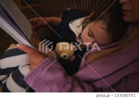 Child Sleeping On Lap With Teddy Bear In Cozy Blanket, Caregiver Reading A Book Child Sleeping On Lap With Teddy Bear In Cozy Blanket, Caregiver Reading A Book 133580751