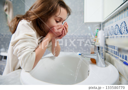 Young Girl Washing Face at Bathroom Sink During Morning Routine 133580770
