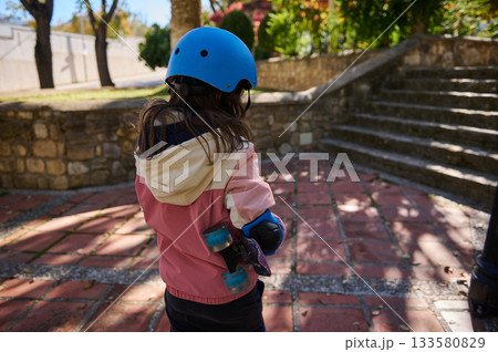 Child With Blue Helmet Holding Skateboard Outdoors Near Stone Steps Child With Blue Helmet Holding Skateboard Outdoors Near Stone Steps 133580829