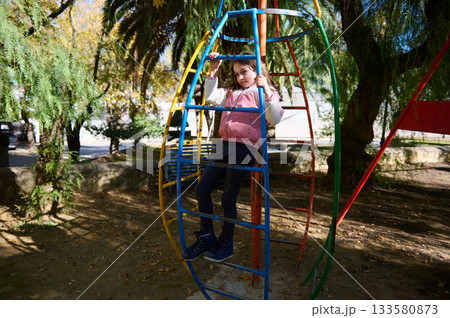 Girl Climbing Colorful Jungle Gym in Park Play Area For Fun Girl Climbing Colorful Jungle Gym in Park Play Area For Fun 133580873
