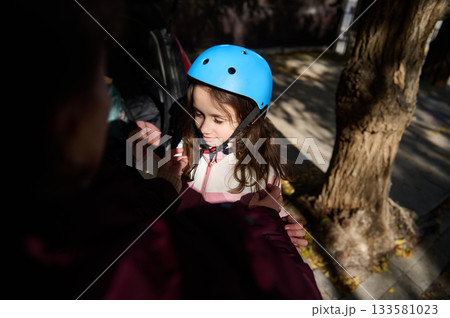 Girl With Blue Helmet Getting Ready For Outdoor Adventure With Help From Adult Girl With Blue Helmet Getting Ready For Outdoor Adventure With Help From Adult 133581023