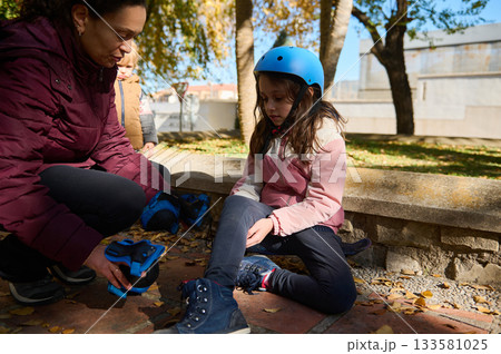 Girl Learning to Skate in Park With Helping Adult, Autumn Leaves and Helmet 133581025