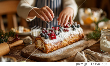Child's hands delicately decorating a buche de noel with berries and powdered sugar on a festive table, capturing the essence of holiday traditions 133581386
