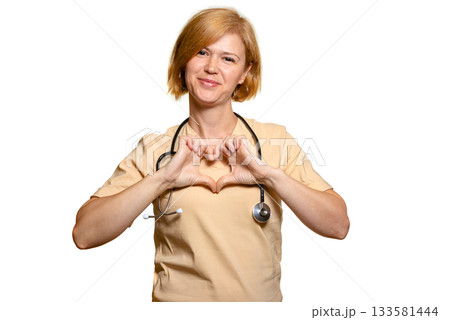 A female doctor, a healthcare worker, shows a heart with both hands folded at chest level. A female doctor, a healthcare worker, shows a heart with both hands folded at chest level. 133581444