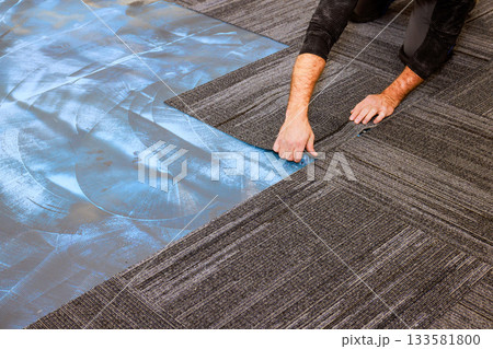Carpenter is laying down carpet tiles in modern office setting, highlighting installation process. Carpenter is laying down carpet tiles in modern office setting, highlighting installation process. 133581800