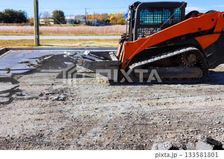 Heavy machinery is breaking up old asphalt in construction site under demolition asphalt Heavy machinery is breaking up old asphalt in construction site under demolition asphalt 133581801