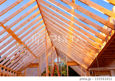 Workers are framing wooden joins rafters roof beams structure at house construction site. Workers are framing wooden joins rafters roof beams structure at house construction site. 133581812