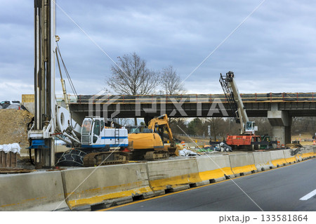 Heavy machinery is actively working on highway bridge as construction efforts continue. Heavy machinery is actively working on highway bridge as construction efforts continue. 133581864