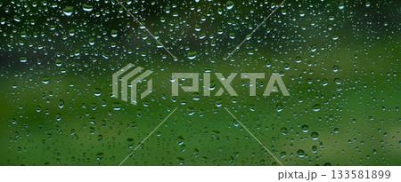 A rainy day window view. Rain drops on window. Condensed rain drop on the car glass window on a rainy day. Dew moisture condensation on wet mirror background. Fresh weather. Water raindrop bg 133581899