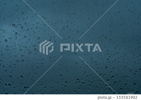 A rainy day window view. Rain drops on window. Condensed rain drop on the car glass window on a rainy day. Dew moisture condensation on wet mirror background. Fresh weather. Water raindrop bg A rainy day window view. Rain drops on window. Condensed rain drop on the car glass window on a rainy day. Dew moisture condensation on wet mirror background. Fresh weather. Water raindrop bg 133581902