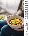 Cozy bowl of chili with avocado slices in hands 133582155