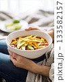 Cozy bowl of chili with avocado slices in hands 133582157