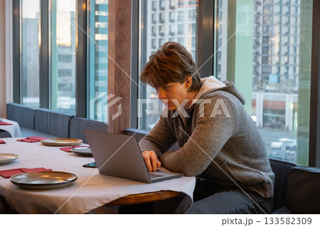 Young man working with laptop in coffee shop. Coffee Break at Cafe Young man working with laptop in coffee shop. Coffee Break at Cafe 133582309
