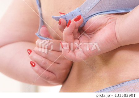 Woman back view putting on her bra lingerie. 133582901