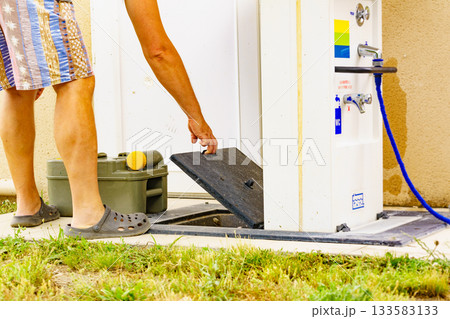 Man emptying caravan tank toilet cassette in dump station. Man emptying caravan tank toilet cassette in dump station. 133583133