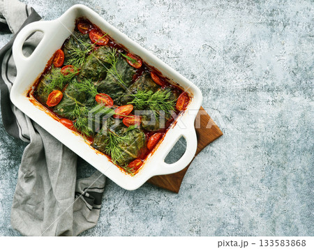 Swiss Chards rolls filled with meat and rice . They are served in a pan with cherry tomatoes, dills 133583868