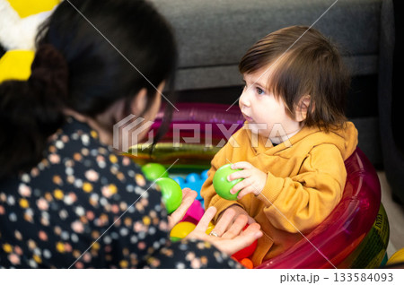 Little one's colorful conversation early afternoon with caregiver in playroom filled with childhood glee and engaging social interaction 133584093