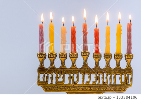 Glowing Hanukkah candles glow on menorah, creating warm atmosphere during Jewish festive event celebrating traditions. 133584106