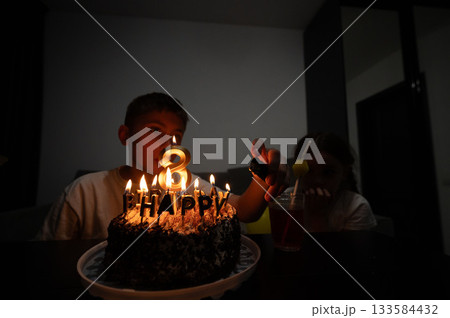 Surrounded by warmth and laughter, a child celebrates their eighth birthday with a chocolate cake adorned with candles and joyful memories in a cozy indoor setting Surrounded by warmth and laughter, a child celebrates their eighth birthday with a chocolate cake adorned with candles and joyful memories in a cozy indoor setting 133584432