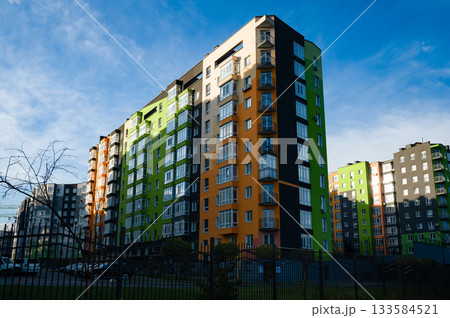 Vibrant modern apartments stand tall against a clear blue sky in a bustling neighborhood filled with life and activity 133584521