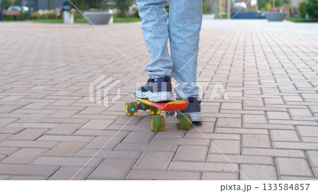 Close-up of teen girl riding a skateboard along a paved street path sport activities and hobby concept 133584857
