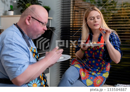 A Culinary Duo Happily Enjoying a Meal Together While Wearing Colorful and Fun Aprons A Culinary Duo Happily Enjoying a Meal Together While Wearing Colorful and Fun Aprons 133584887