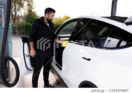 Young caucasian male cleaning white car at gas station 133584967