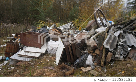 abandoned metal debris, rusty scrap amid neglected surroundings, decaying objects scattered across overgrown terrain, wornout appliances and metal remnants in forgotten urban space 133585183