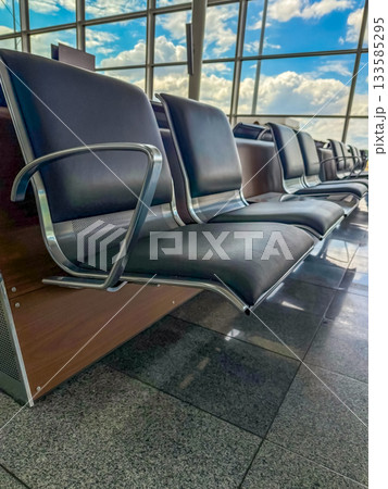 Empty airport waiting area with modern chairs and glass windows Empty airport waiting area with modern chairs and glass windows 133585295