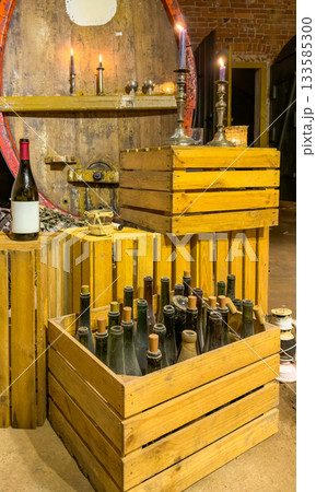 Old wine cellar interior with bottles, candles and wooden crates 133585300
