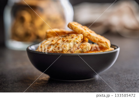 Crunchy salted crackers in bowl on black table. 133585472
