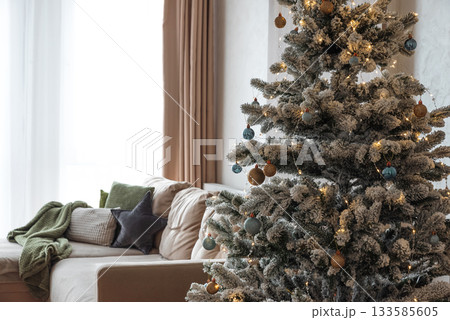 Festive Living Room with Snow-Flocked Christmas Tree and Cozy Decor Festive Living Room with Snow-Flocked Christmas Tree and Cozy Decor 133585605